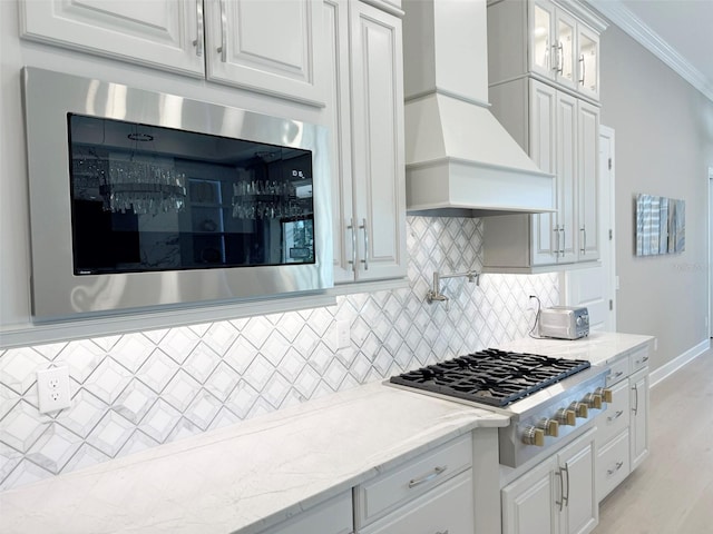 5305 Brookgrove Dr, Sarasota, FL 34238 - kitchen with custom range hood, appliances with stainless steel finishes, white cabinets, crown molding, and decorative backsplash