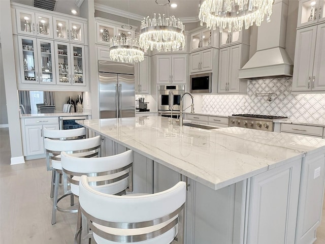 5305 Brookgrove Dr, Sarasota, FL 34238 - kitchen with built in appliances, custom range hood, ornamental molding, an inviting chandelier, and a sink