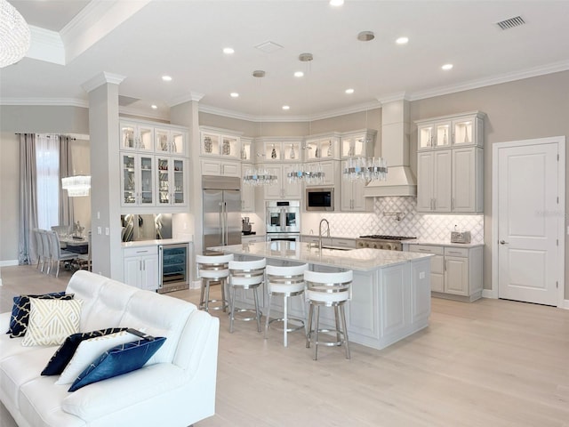 5305 Brookgrove Dr, Sarasota, FL 34238 - kitchen featuring a large island with sink, decorative backsplash, wine cooler, built in appliances, and a kitchen bar