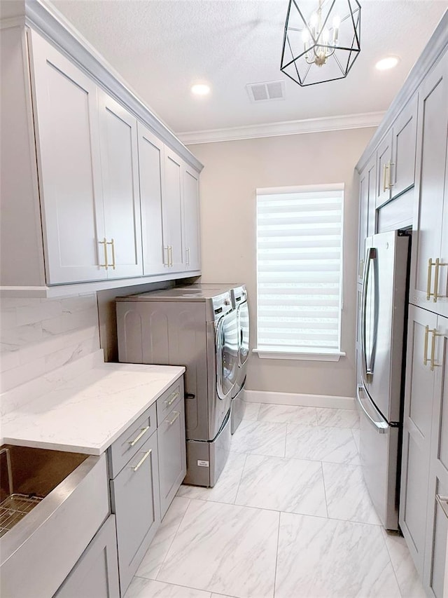 5305 Brookgrove Dr, Sarasota, FL 34238 - laundry area with visible vents, marble finish floor, crown molding, a notable chandelier, and independent washer and dryer