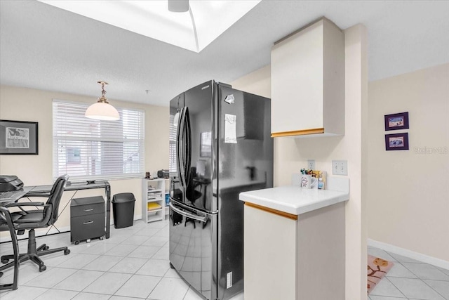 kitchen with black fridge, ceiling fan, decorative light fixtures, white cabinets, and light tile patterned flooring