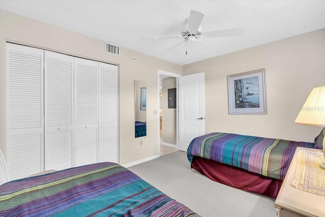 carpeted bedroom with a textured ceiling, a closet, and ceiling fan