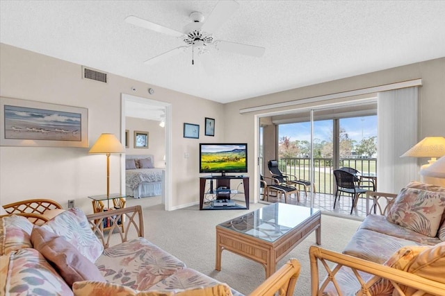 carpeted living room with ceiling fan and a textured ceiling