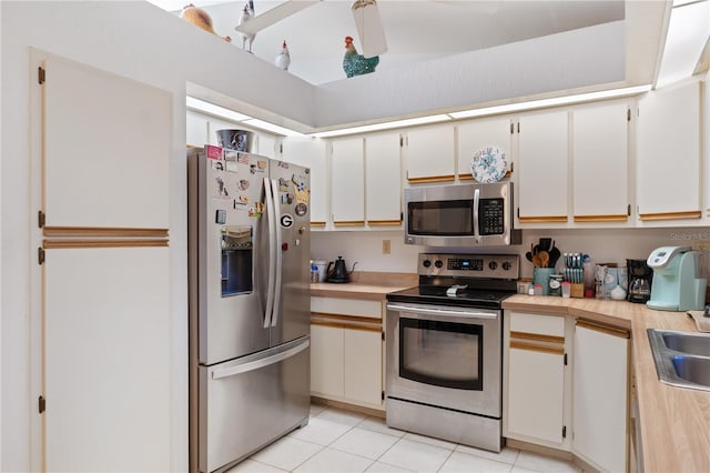 kitchen featuring light tile patterned floors, stainless steel appliances, sink, and white cabinets