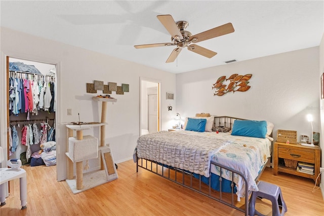 bedroom with wood-type flooring, a walk in closet, ceiling fan, and a closet