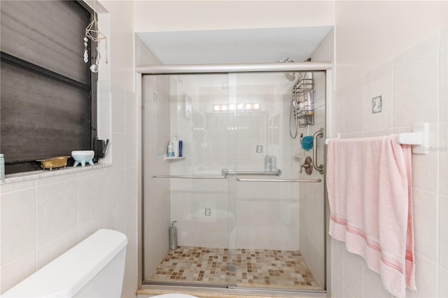 bathroom with walk in shower, toilet, and tile walls