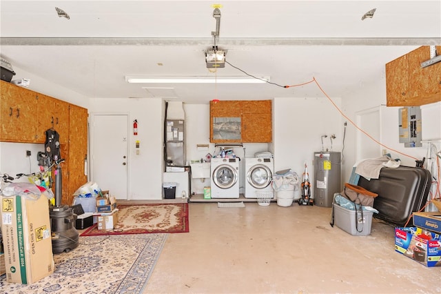 garage featuring sink, a garage door opener, electric panel, independent washer and dryer, and electric water heater