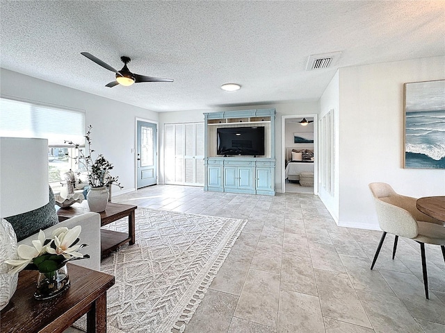 tiled living room featuring ceiling fan and a textured ceiling