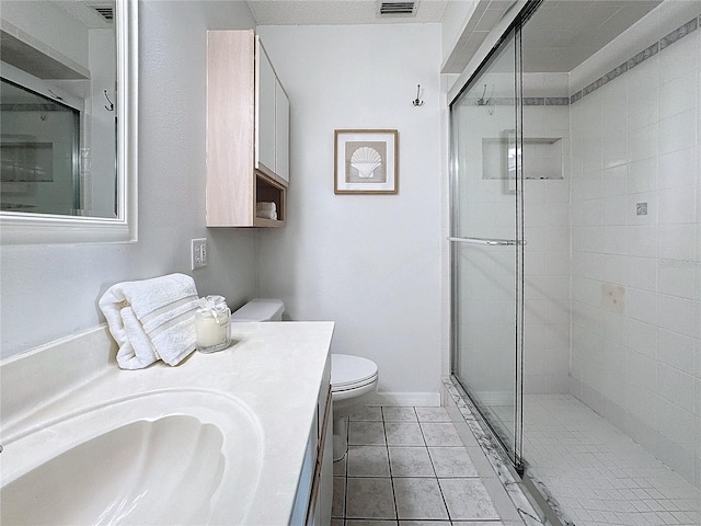 bathroom with tile patterned floors, vanity, toilet, and a shower with door