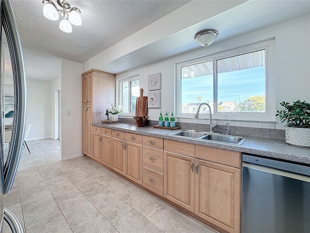 kitchen with appliances with stainless steel finishes, a textured ceiling, a wealth of natural light, and sink