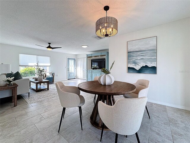 dining area with a textured ceiling and ceiling fan with notable chandelier