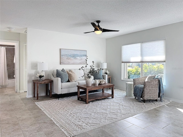 living room with ceiling fan, light tile patterned flooring, and a textured ceiling