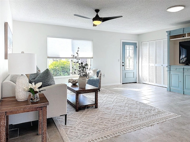 tiled living room with a textured ceiling and ceiling fan