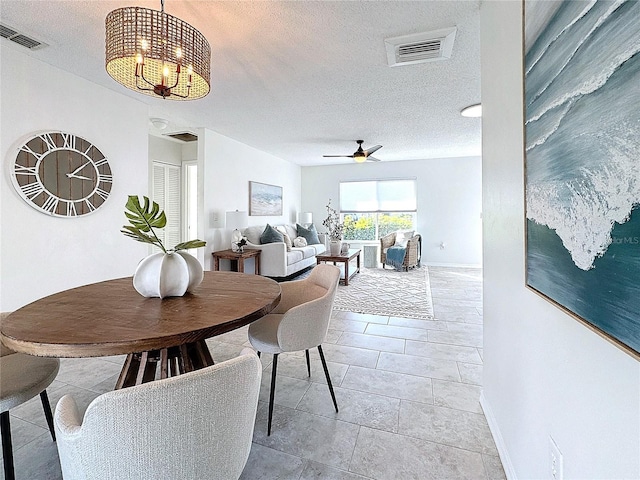 dining space featuring a textured ceiling, ceiling fan with notable chandelier, and light tile patterned floors