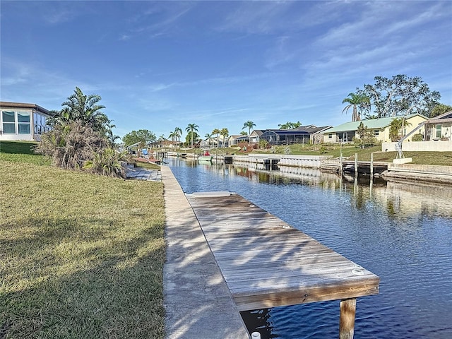 view of dock with a lawn and a water view