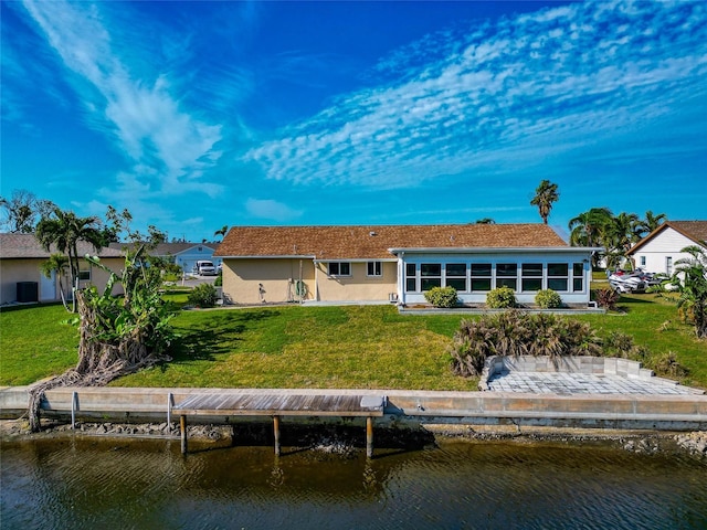 back of property with a lawn and a water view