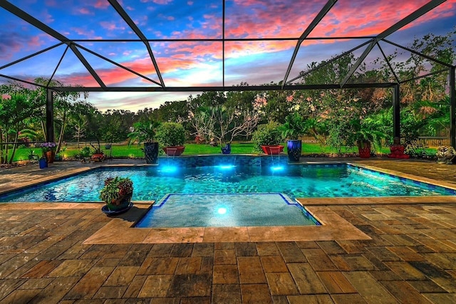 pool at dusk featuring glass enclosure, pool water feature, and a patio