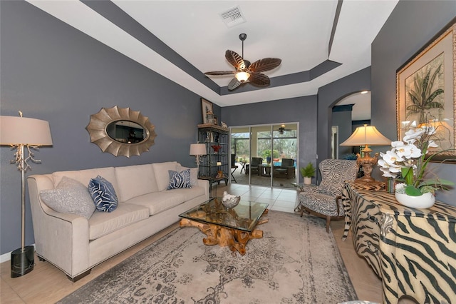 living room featuring ceiling fan, a raised ceiling, and light tile patterned floors