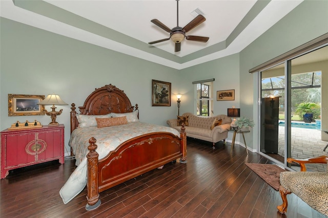 bedroom featuring access to outside, a raised ceiling, ceiling fan, and dark hardwood / wood-style floors