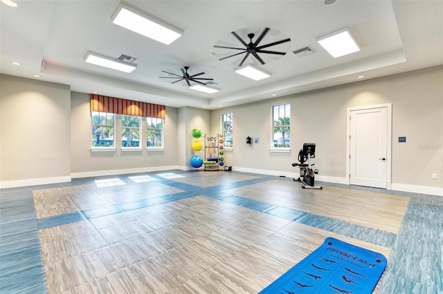 workout room featuring ceiling fan and a raised ceiling