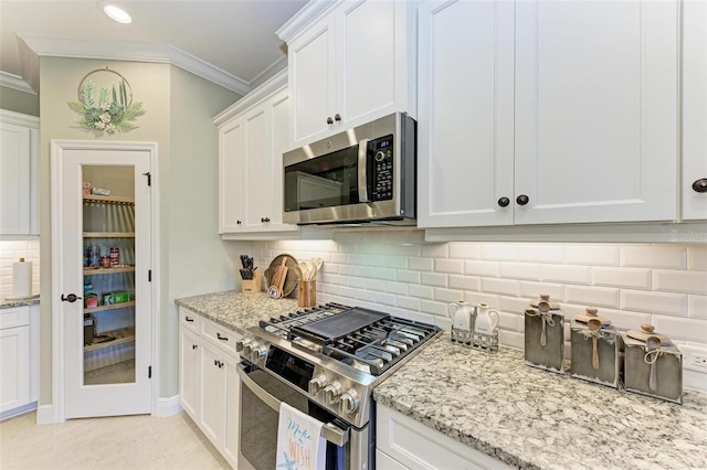 kitchen with light stone countertops, white cabinets, crown molding, and stainless steel appliances