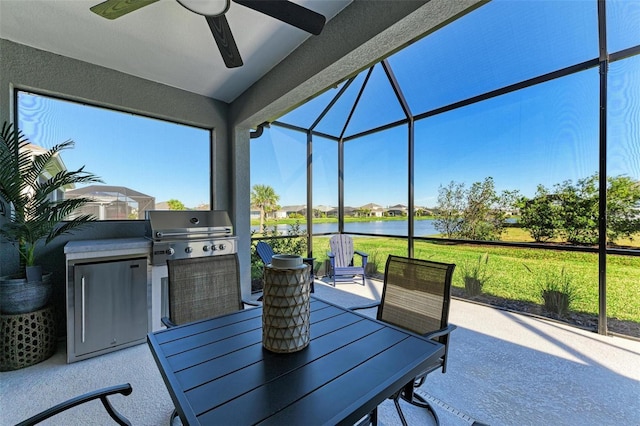 view of patio featuring a grill, a water view, exterior kitchen, a lanai, and ceiling fan