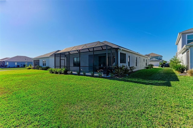 back of property with glass enclosure and a lawn