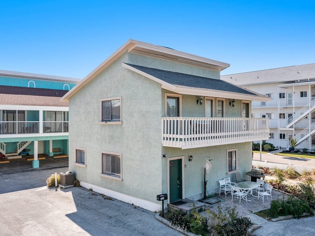 rear view of house with a balcony, central AC unit, and a patio area