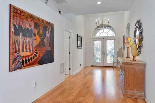 entrance foyer featuring a notable chandelier, light hardwood / wood-style floors, and french doors