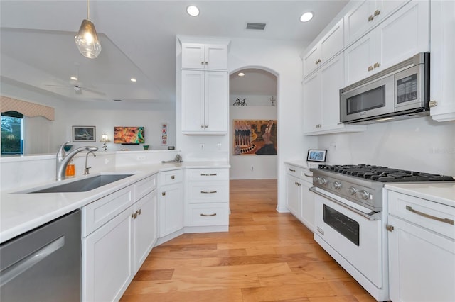 kitchen featuring hanging light fixtures, sink, light hardwood / wood-style flooring, appliances with stainless steel finishes, and white cabinetry