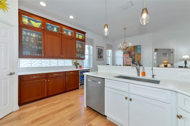 kitchen featuring pendant lighting, white cabinets, stainless steel dishwasher, and sink