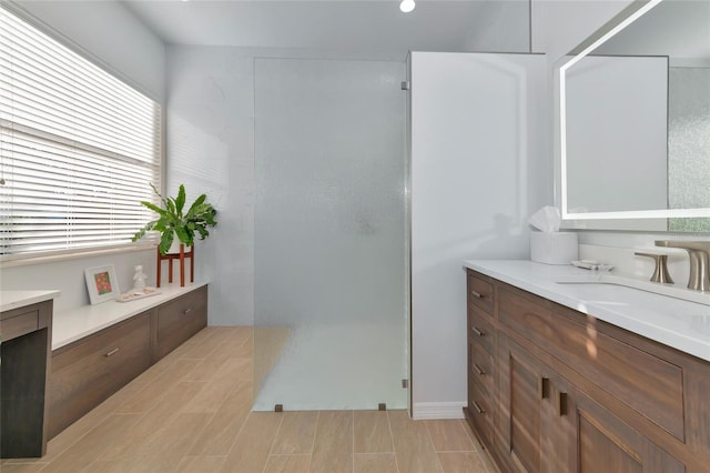 bathroom with vanity, walk in shower, and a healthy amount of sunlight