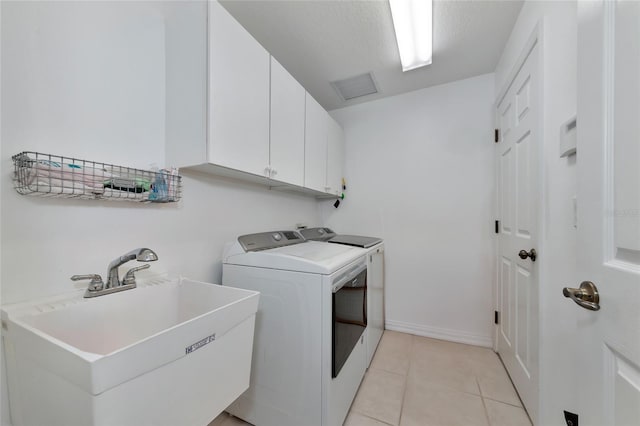 laundry room with washer and clothes dryer, cabinets, light tile patterned floors, and sink