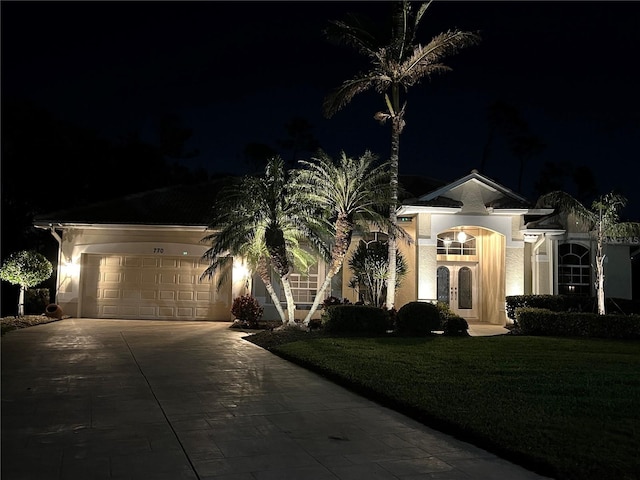 single story home featuring a garage and a lawn