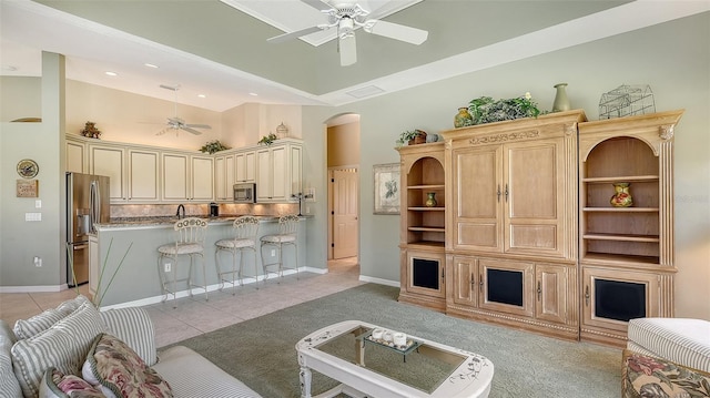 living room with light tile patterned floors, ceiling fan, and a high ceiling