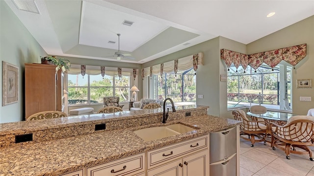 kitchen with light stone countertops, sink, a raised ceiling, and light tile patterned floors