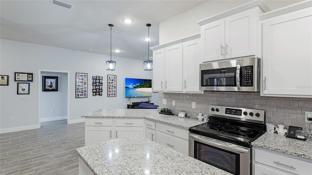 kitchen with decorative light fixtures, backsplash, stainless steel appliances, and white cabinetry