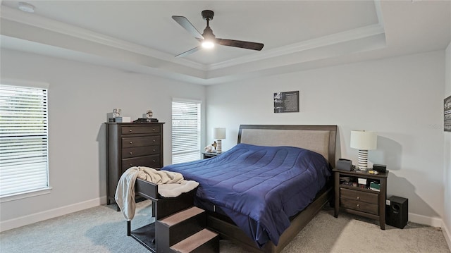 bedroom featuring ceiling fan, a raised ceiling, light carpet, and crown molding