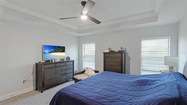 bedroom featuring ceiling fan, light colored carpet, crown molding, and a tray ceiling