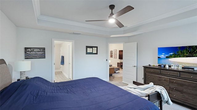 bedroom with connected bathroom, a tray ceiling, ceiling fan, and crown molding