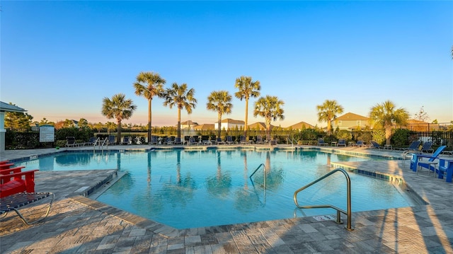 pool at dusk with a patio area