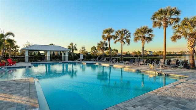 pool at dusk featuring a patio