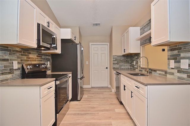 kitchen with white cabinets, appliances with stainless steel finishes, light hardwood / wood-style floors, and sink