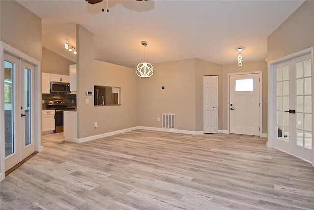 foyer with ceiling fan, vaulted ceiling, light hardwood / wood-style flooring, and french doors