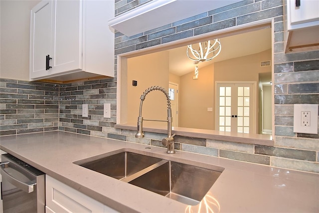 kitchen with pendant lighting, white cabinets, sink, vaulted ceiling, and stainless steel dishwasher