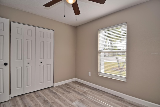 unfurnished bedroom with ceiling fan, light hardwood / wood-style floors, a textured ceiling, and a closet