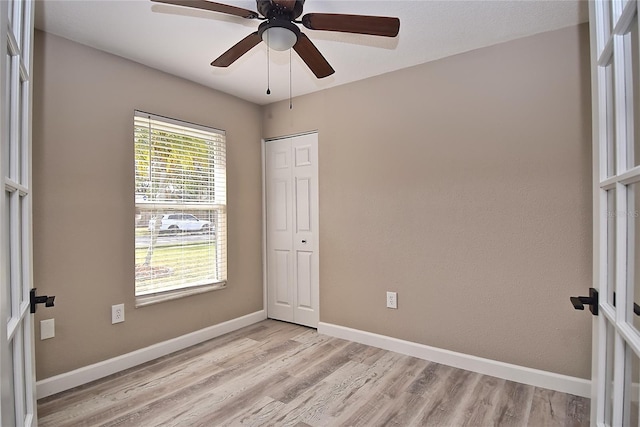 unfurnished bedroom with ceiling fan, light wood-type flooring, french doors, and a closet