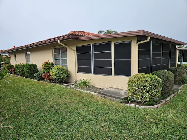 view of side of home featuring a lawn and a sunroom