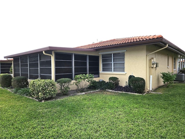 view of property exterior featuring a sunroom, central AC unit, and a yard