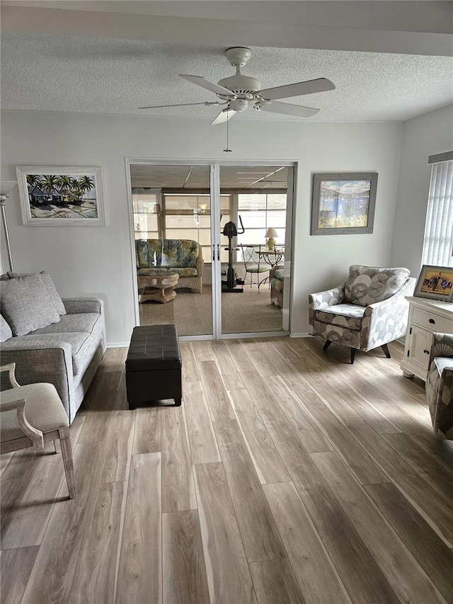 living room with ceiling fan, a textured ceiling, and hardwood / wood-style flooring